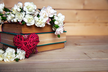 gentle carnation in the old book on a wooden background. Valenti