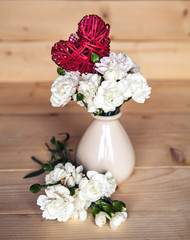 delicate bouquet of carnations in vintage vase with heart