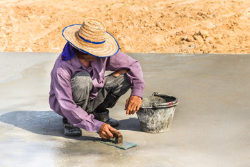 construction worker spreading smooth wet concrete with trowel