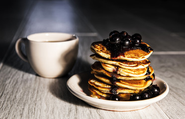 Picture of few pancakes with blackberries and cup of tea on wood