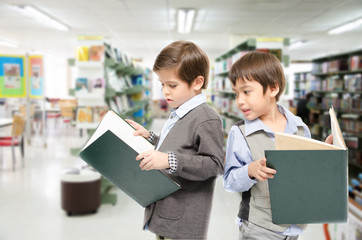 Fototapeta na wymiar Little boys reading books in the library
