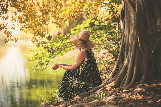 Woman sitting under tree by the river