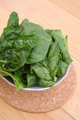 spinaci freschi in foglie su tavolo di legno