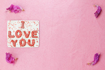 I love you words on pink background with rose petals
