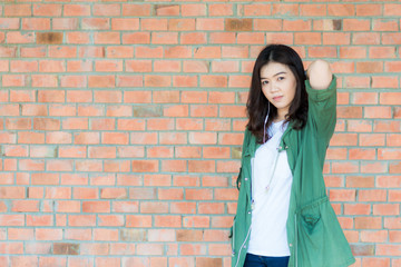 Young asian woman wear green coat stand in front of brick wall b