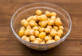 Chickpeas on bowl on wooden table seen from above
