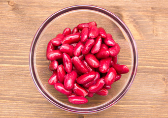 Red beans on bowl on wooden table seen from above