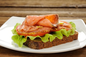 Rye bread sandwich with red fish, tomatoes and mustard