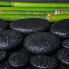 Obraz na płótnie Canvas spa concept of zen basalt stones and bamboo with dew, closeup