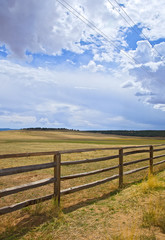Fototapeta na wymiar Wooden fence on a rural farm pasture fields