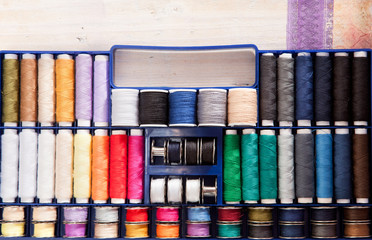 Bunt gefüllter Nähseidenkoffer auf einer Holzkiste