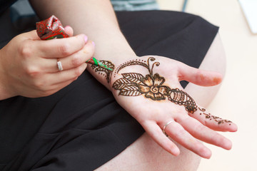 Woman paints henna on her hand