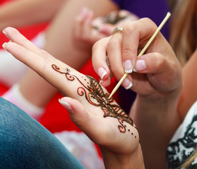 Caucasian woman applying henna tattoo