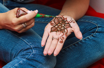 Woman dressed in jeans applying henna