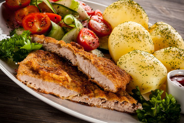 Fried pork chops, boiled potatoes and vegetable salad