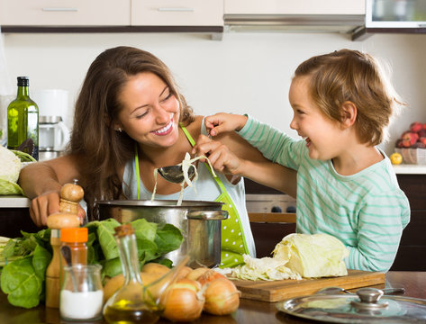 Woman with baby cooking at kitchen