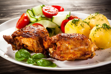 Barbecued chicken legs with boiled potatoes and vegetables
