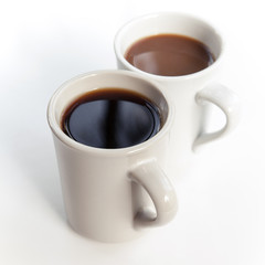 Two cups full of coffee stand on the table