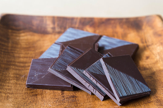 horizontal view of broken chocolate bar on wooden plate.