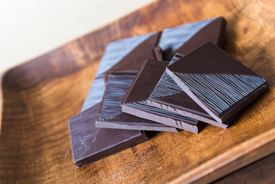 Picture of broken chocolate bar on wooden plate.