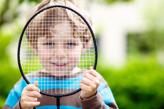Little cute funny kid boy playing badminton in domestic garden