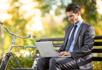 Businessman with bicycle working on laptop