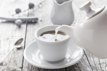 Obraz na płótnie Canvas pouring milk from jug cup black coffee