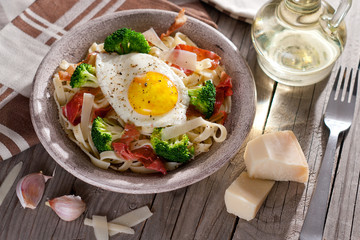 Tagliatelle pasta with broccoli, prosciutto and fried egg.