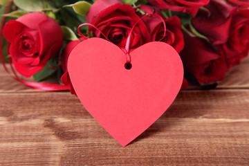 Valentine background of gift tag and red roses on wood