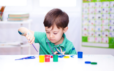 Little boy is playing with paints