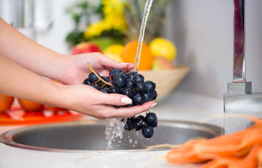 woman's hands washing a fresh grapes
