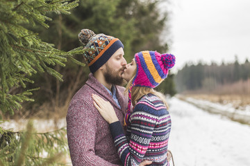 Young peaople are kissing in winter forest - 77288887