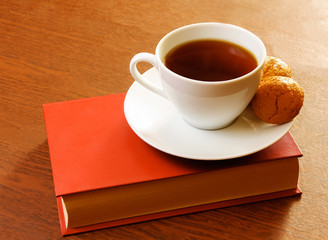Tea cup with sweet cookie and book