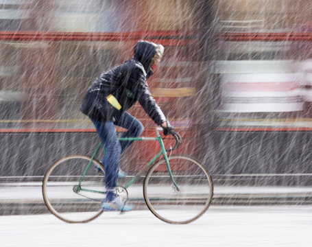 Man on bicycle in the city in snowy winter day