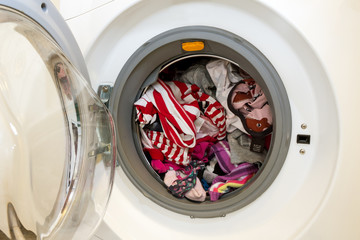 Closeup of an open washing machine full of dirty laundry to wash
