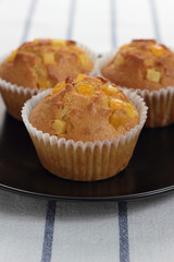 Muffin with orange zest on a black plate.