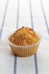 Muffin with orange zest on a white and blue tablecloth.