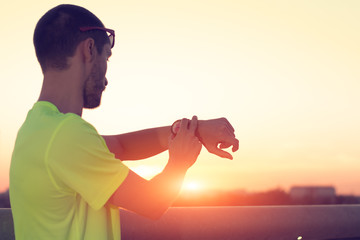 Urban jogger checking his watch on a bridge. Focus on the watch.