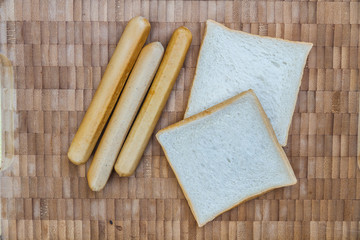 Bread and sausage on wood table. Top view.
