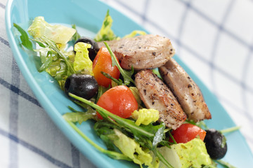 Green salad with tomatoes, olives and pieces of sirloin.