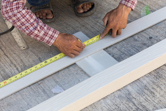 carpenter using ruler to draw a line marking on a wood board