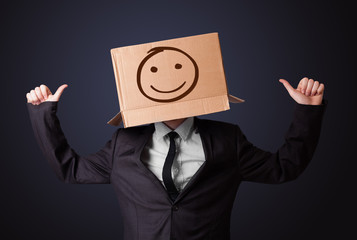 Businessman gesturing with a cardboard box on his head with smil