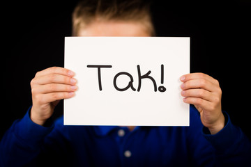 Child holding sign with Danish word Tak - Thank You