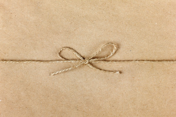 Fototapeta na wymiar string or twine tied in a bow on kraft paper background