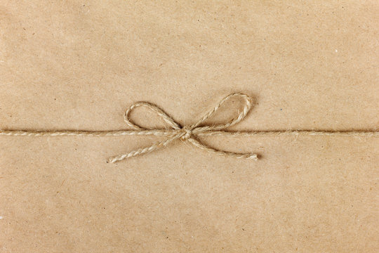 string or twine tied in a bow on kraft paper background