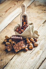 milk chocolate with hazelnuts and walnuts in a sack on a wooden
