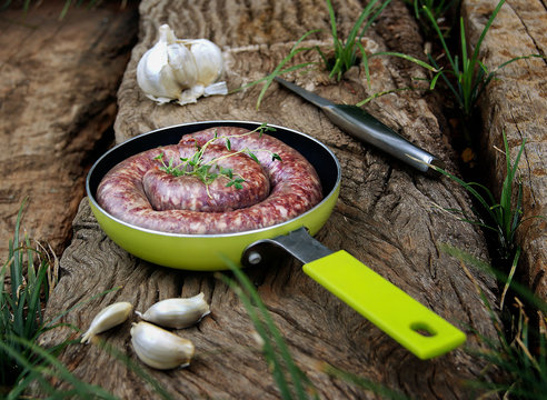 raw beef sausage in a frying pan with garlic
