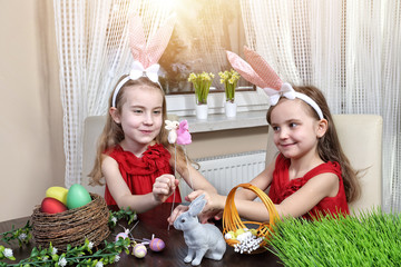 Obraz na płótnie Canvas two sisters playing in the tuning of the Easter basket