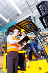 Asian forklift truck driver and foreman in storage