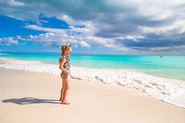 Adorable little girl on white beach during tropical vacation